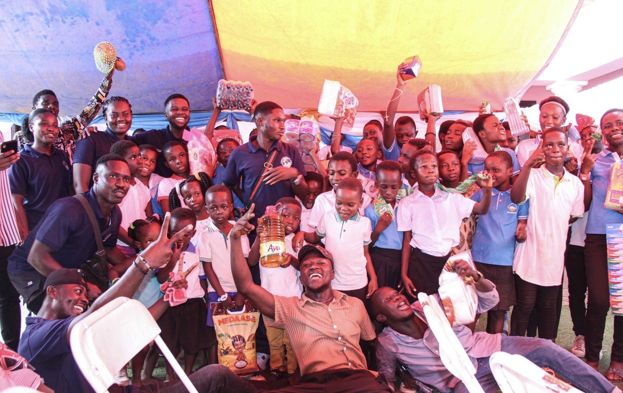 IWF volunteers and children celebrating with donated food items at an orphanage outreach