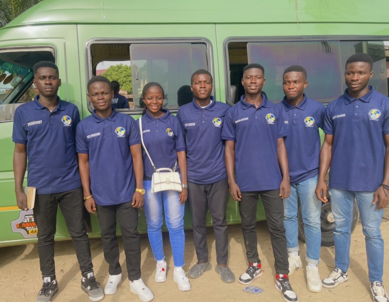 IWF executive team in branded navy polo shirts beside a green bus